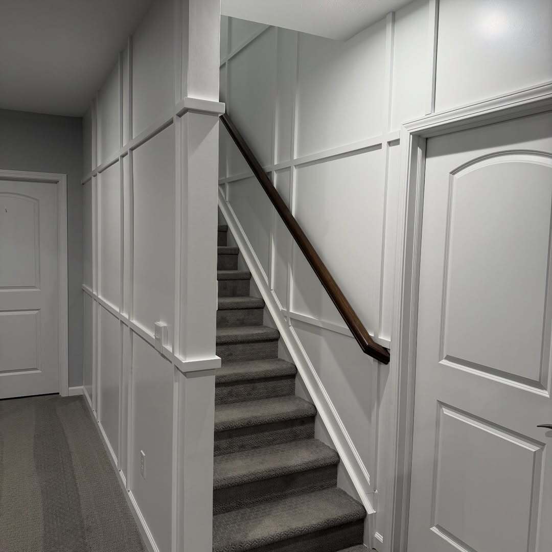 Discover how statement stairwell carpentry and soft plaid wainscoting transform blank staircases into luxury architectural features. Professional trim design increases home value & first impressions.