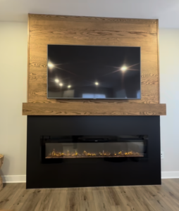 Fireplace build-out with custom tongue-and-groove red oak and a sleek black firebox face. See how modern lines and traditional warmth create a balanced, custom feature wall for 2026 homes.