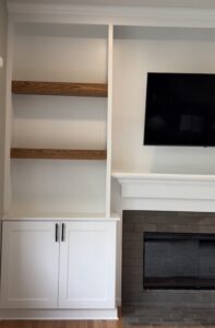 Fireplace built-ins can solve a flush wall with custom cabinetry, matched wood shelves, crown molding, TV placement, and careful finish carpentry.
