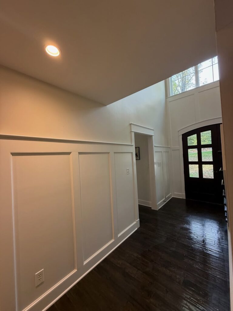 Foyer trim carpentry can turn a basic entry into a custom first impression with Craftsman style, rabbeted molding, accent walls, professional painting, and detailed finish work.