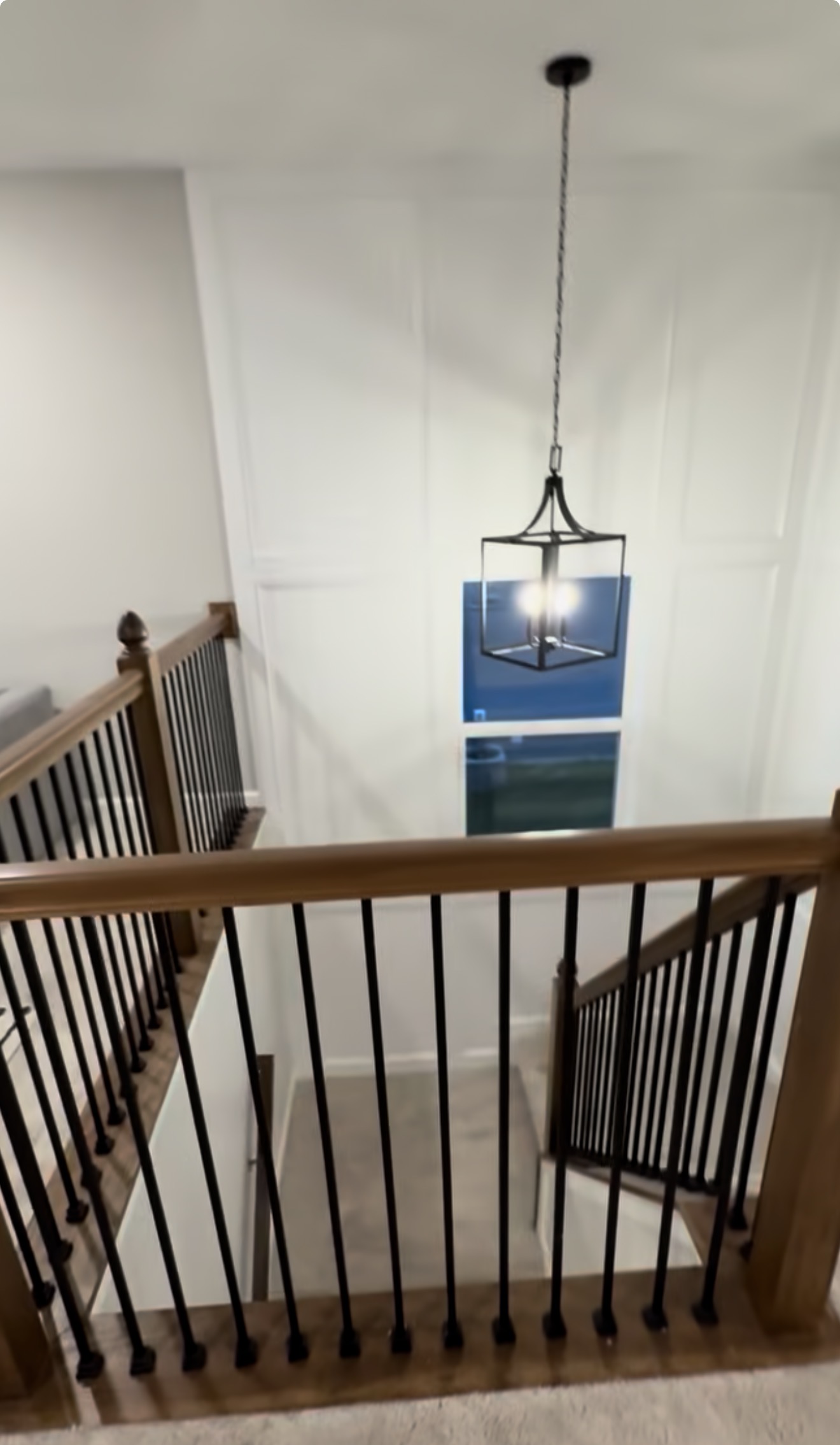 Stairwell trim carpentry can turn a blank wall into a lasting feature with a custom grid layout, inset base cap molding, traditional profiles, and a clean painted finish.