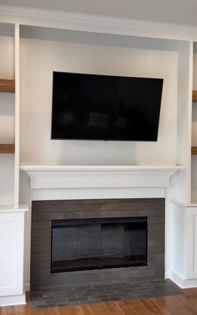 Fireplace built-ins can solve a flush wall with custom cabinetry, matched wood shelves, crown molding, TV placement, and careful finish carpentry.