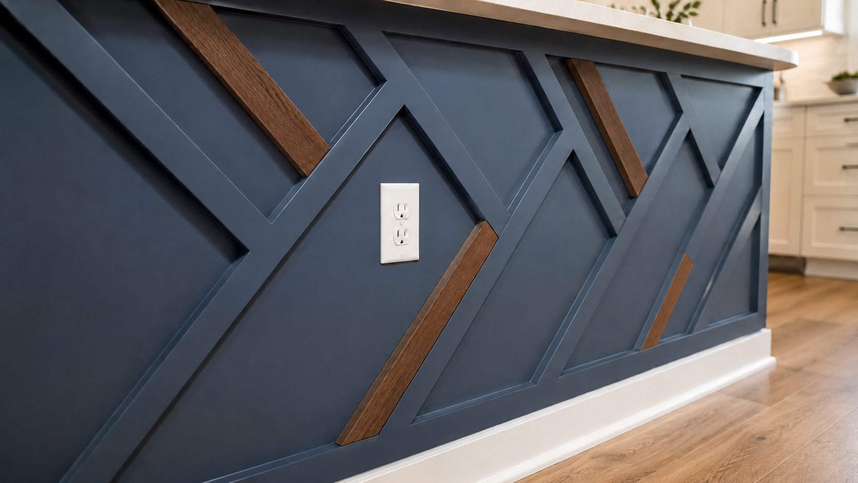 Close-up of diagonal painted battens meeting stained white oak accents on a blue geometric kitchen island panel with a flush outlet