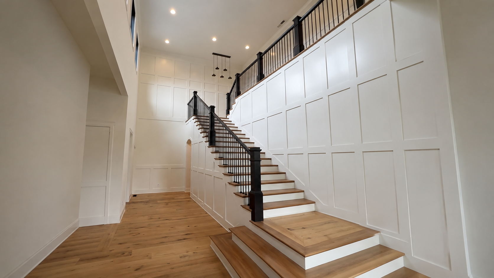 Full-height square wall paneling laid out like picture frame molding on a two-story staircase by Radford Woodworks