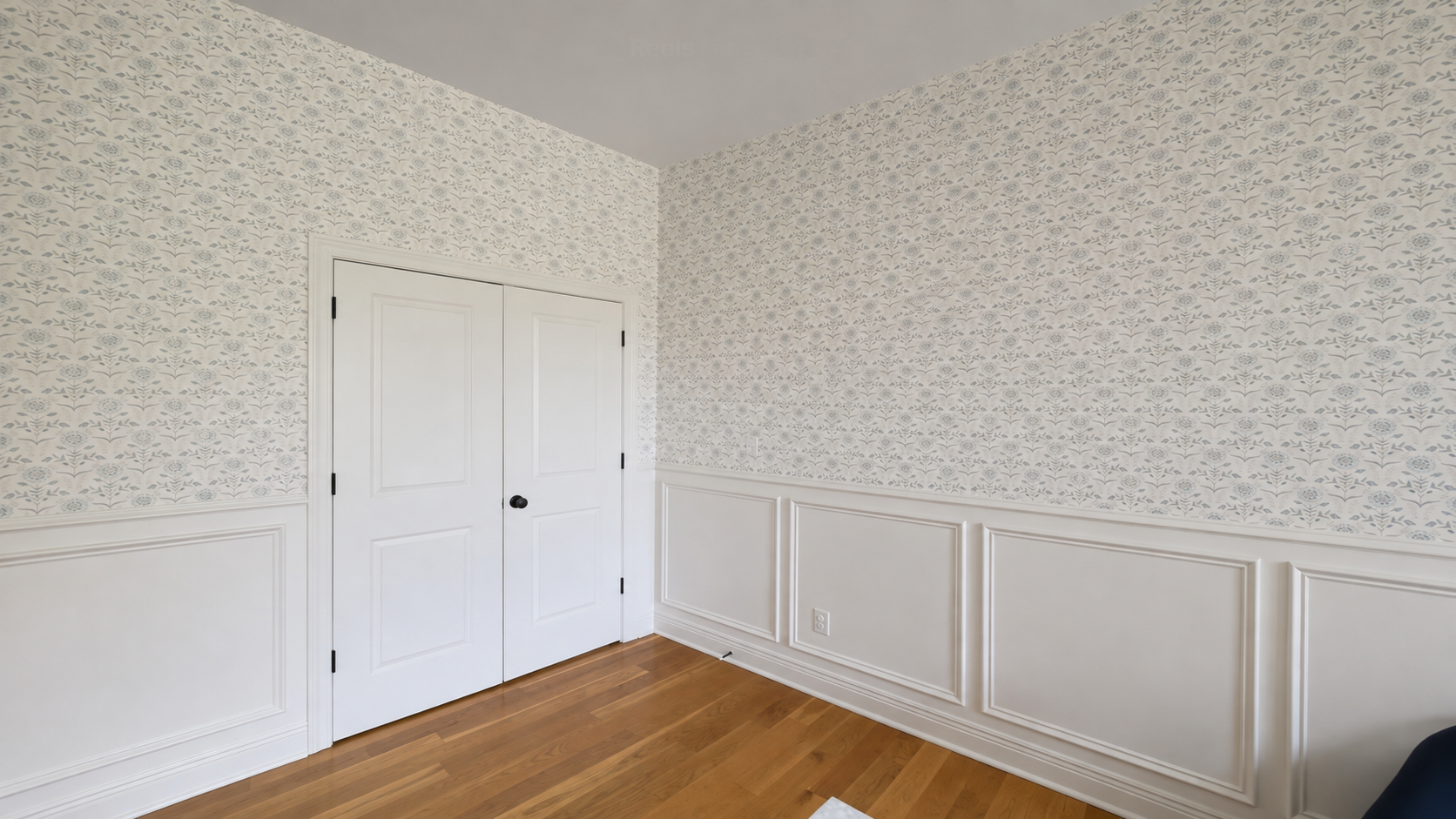 Small-scale blue-gray floral wallpaper above white picture-frame wainscoting and double closet doors in a central Indiana bedroom by Radford Woodworks